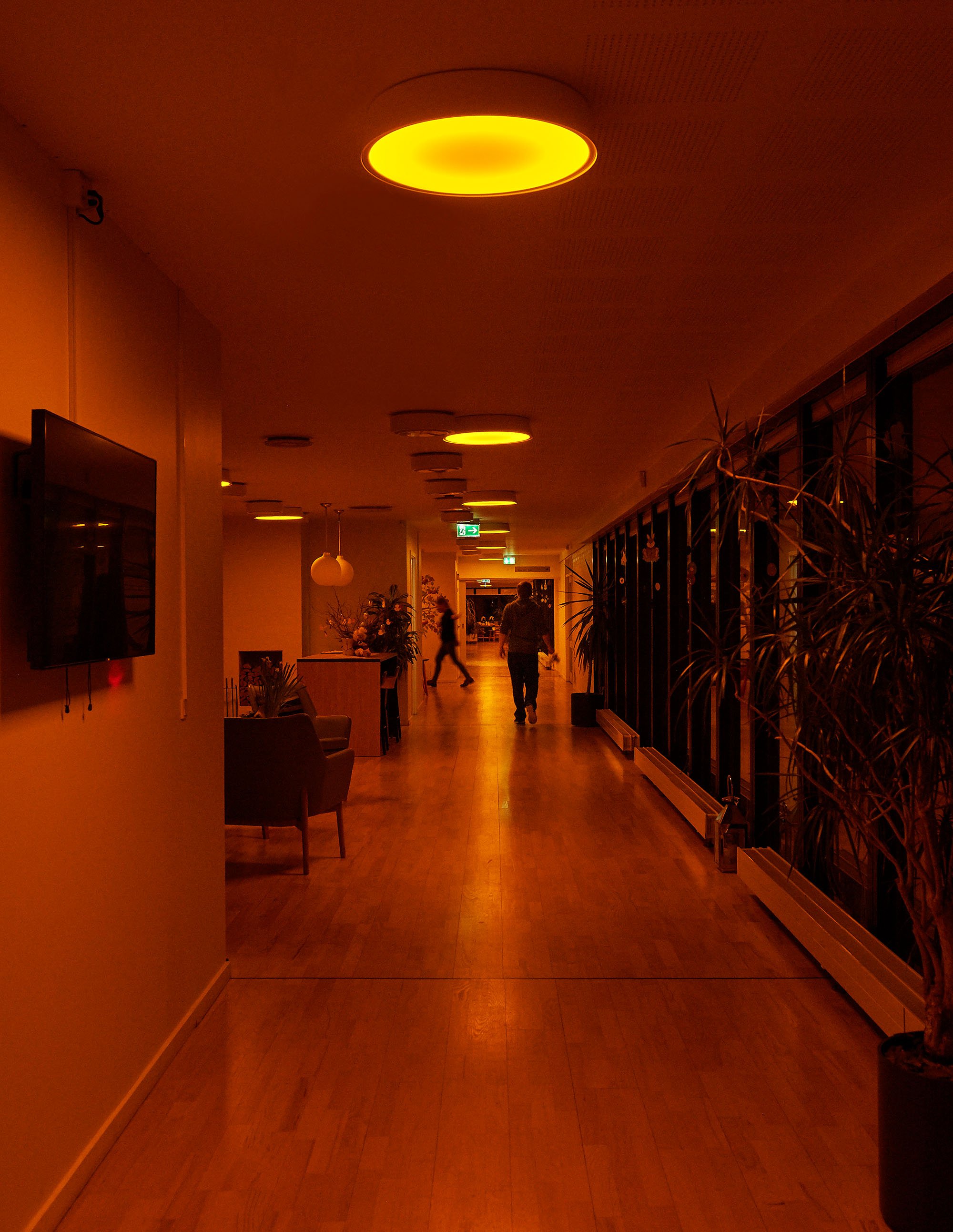 Staff walking in the hallways of a nursing homw with circadian lighting in the ceiling