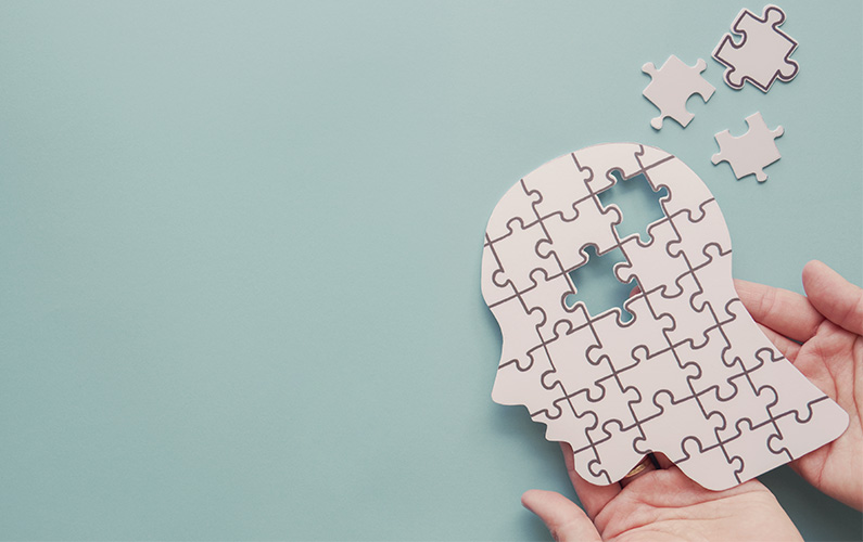 Hands are holding a puzzle shaped like a head with some missing pieces