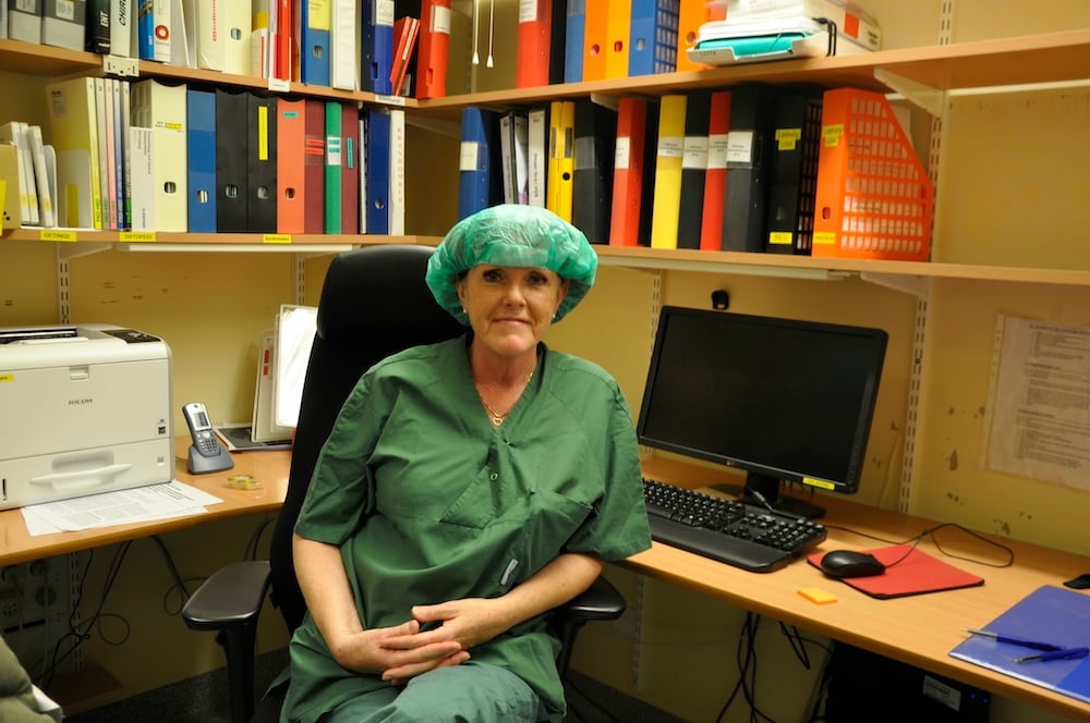 Anja Fönslund, tekniskt ansvarig sjuksköterska, sitter vid sitt skrivbord iklädd uniform