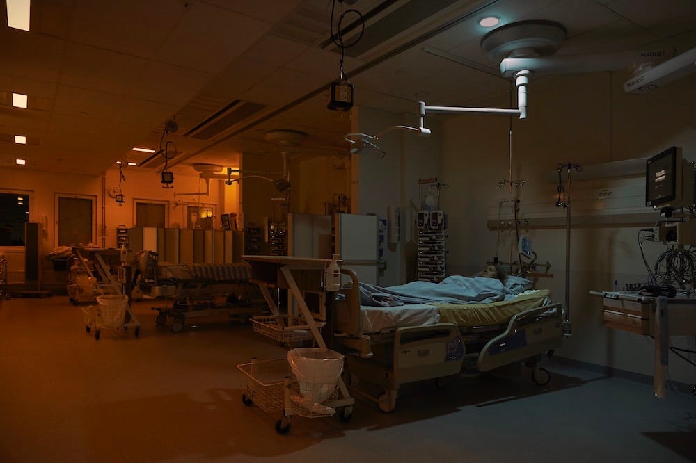 En patient ligger i en sjukhussäng med punktljus ovanför och dygnsrytmljus på den kvarvarande avdelningen