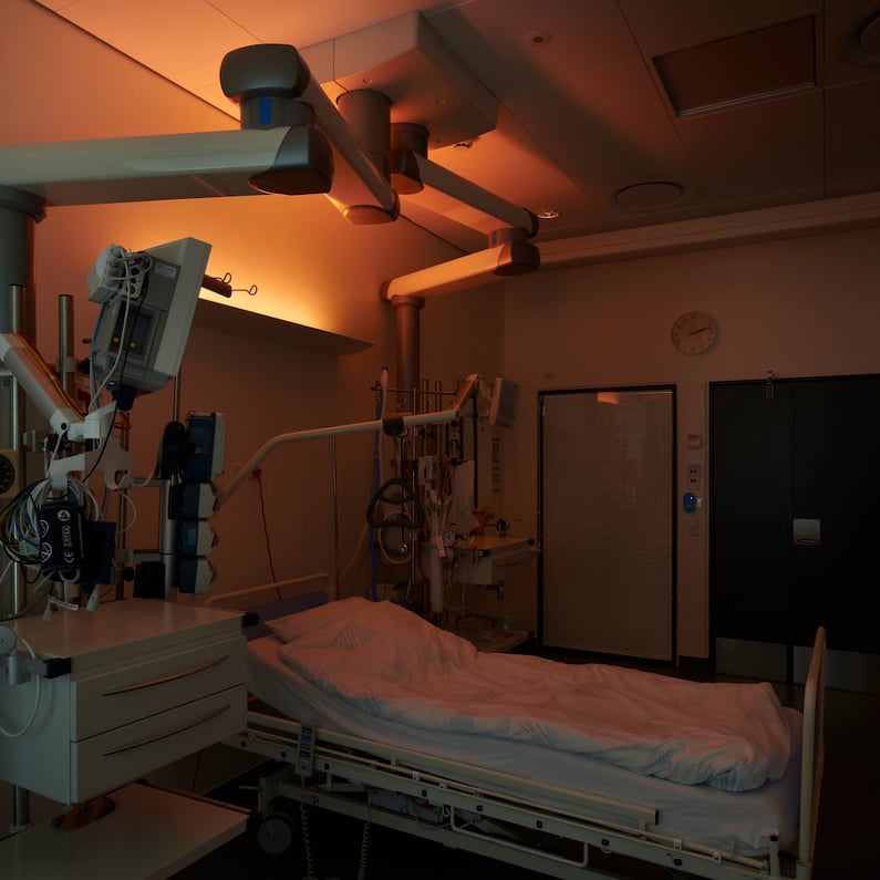 Hospitalsstue med hospiitalsseng og døgnrytmelys med natlys på væggen