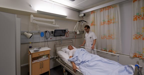 Læge Anders West tilser patient i hospitalsstue på Glostrup Hospital hvor Chromavisos døgnrytmelys er installeret