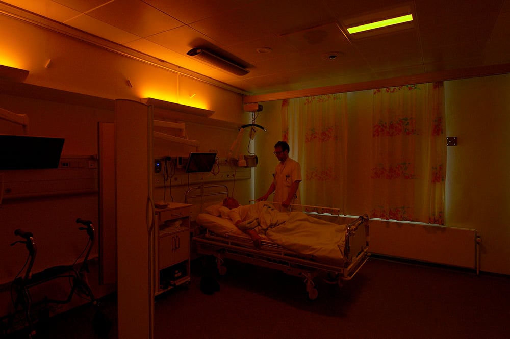 Anders West attends to a patient in a hospital room with amber circadian light at Rigshospitalet Glostrup