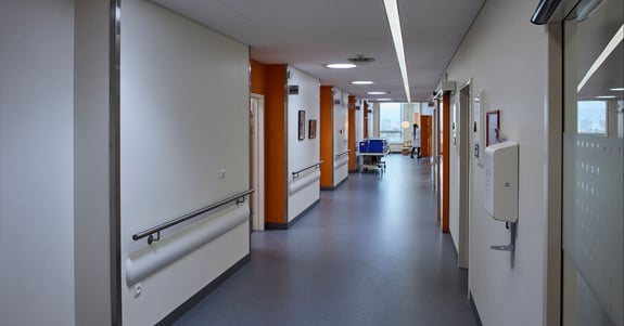 Lang gang på Rigshospitalet med døgnrytmelys i loftet og en sygeplejesker der arbejder 
