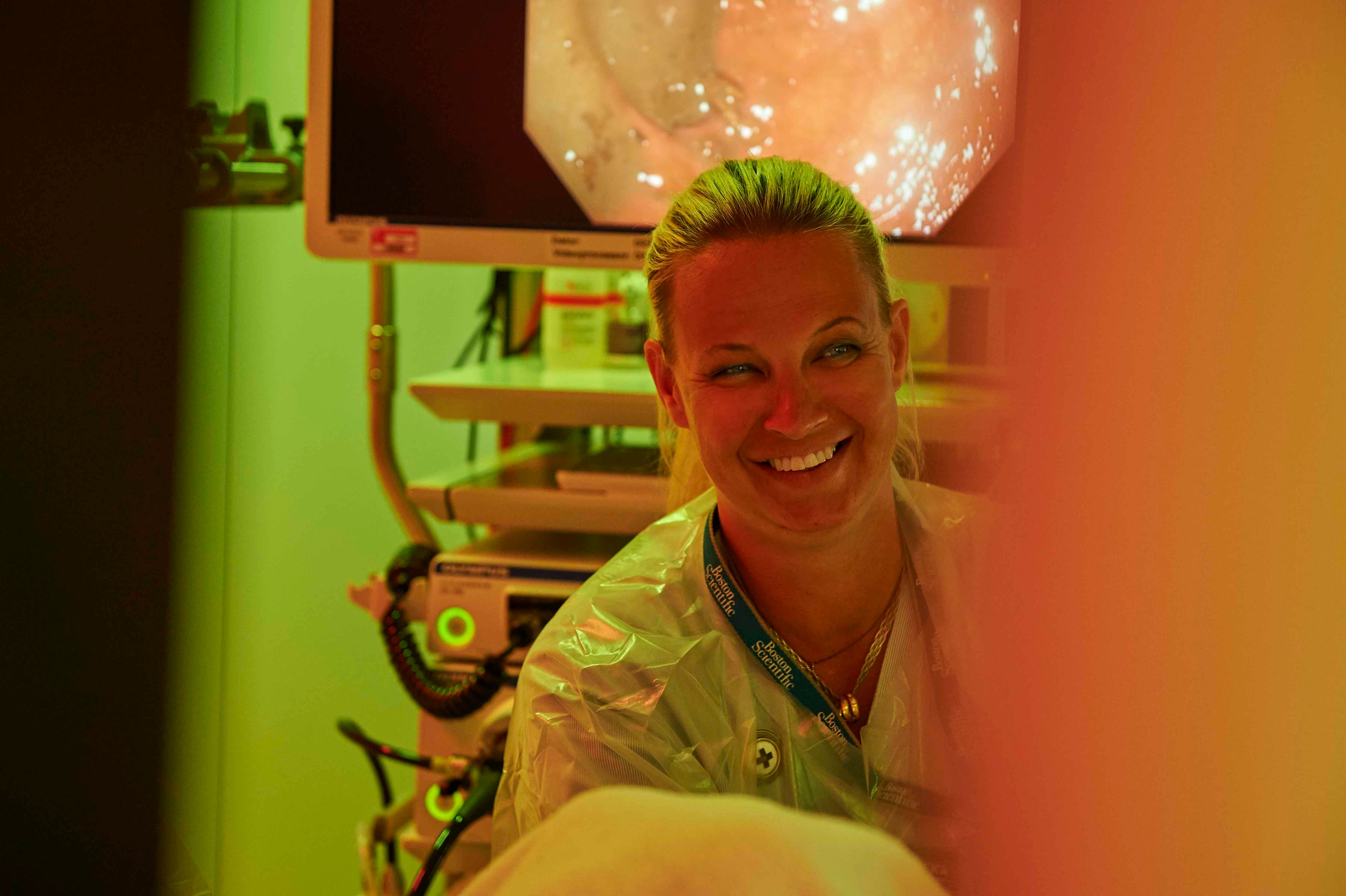 Smilende sygeplejerske der udfører medicinsk indgreb på patient i ergonomisk lys