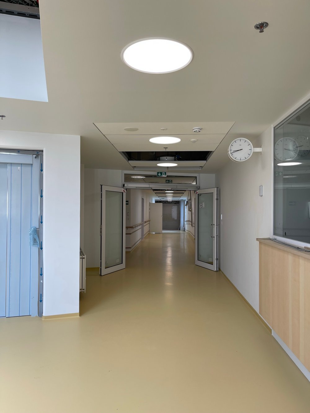 Åben dør på lang hospitalsgang i Torshavn, hvor Chromavisos lysløsninger hænger i loftet