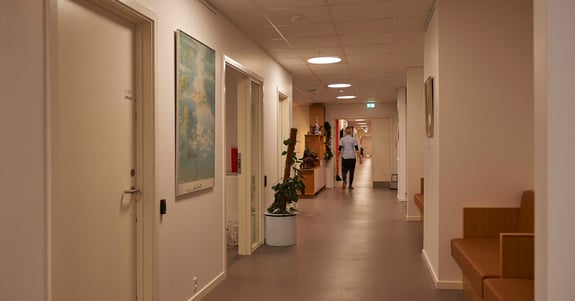 Sosu-medarbejder går på en lang gang på et plejehjem med døgnrytmelys fra Chromaviso i loftet