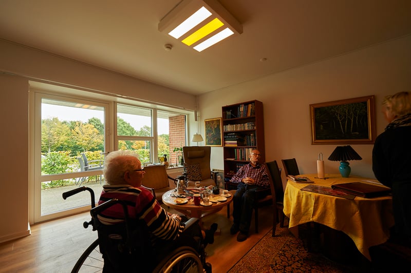 To ældre borgere drikker kaffe i deres plejebolig med Chromavisos døgnrytmelys