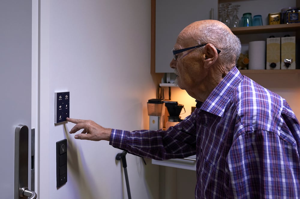 Ældre mand på plejehjem anvender Chromavisos betjeningspanel til døgnrytmelys